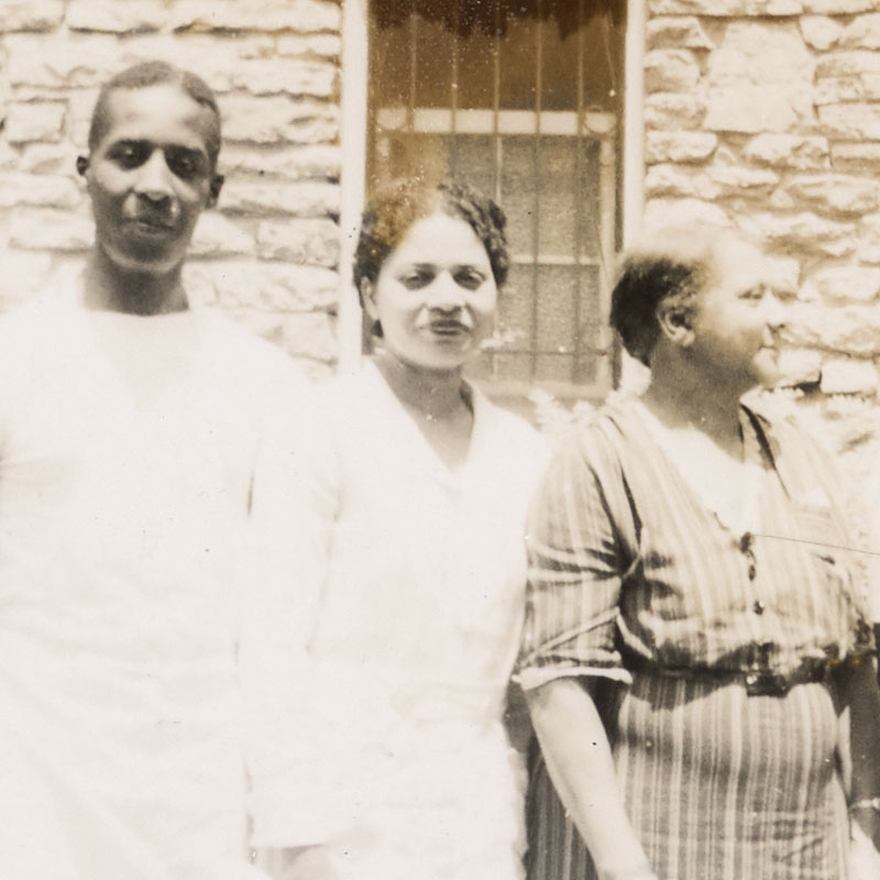 Three African American men and women pose for a photograph in front of a stone building